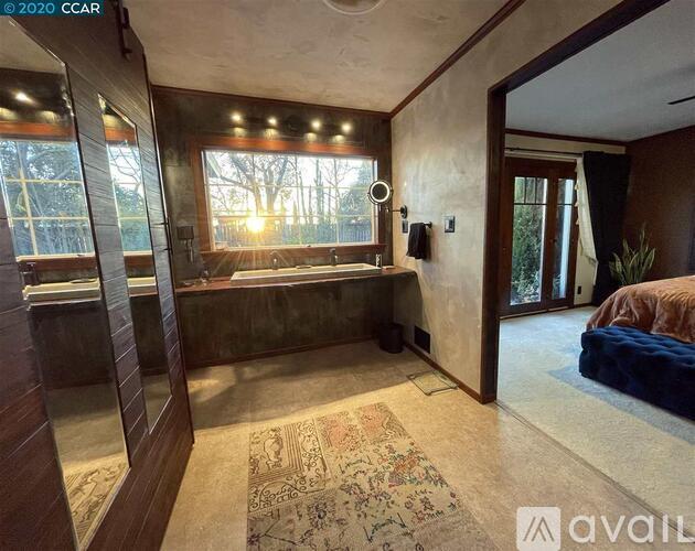 A bedroom with a large bed and a window with sunlight shining through.