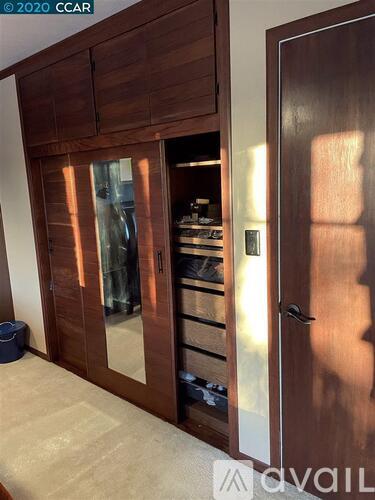 A wooden cabinet with a glass door is open, revealing a kitchen inside.
