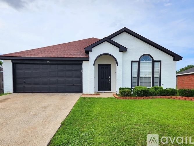 A white house with a black garage door is for sale.