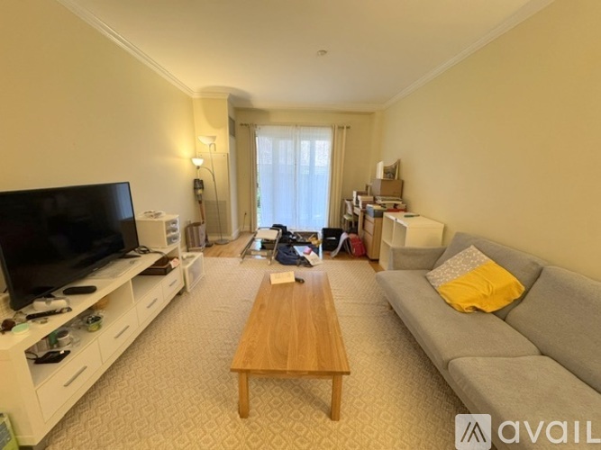A living room with a grey couch, a wooden coffee table, and a television on a white stand.