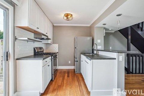 A kitchen with white cabinets and a wooden floor.
