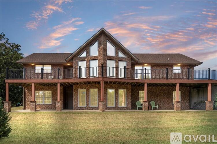A house with a large front porch and a balcony overlooking a grassy area.