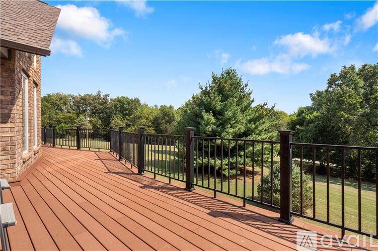 A wooden deck with a black railing and a bench.