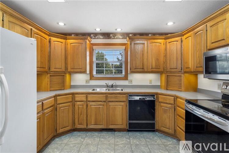 A kitchen with wooden cabinets and a black dishwasher.