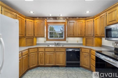 A kitchen with wooden cabinets and a black dishwasher.