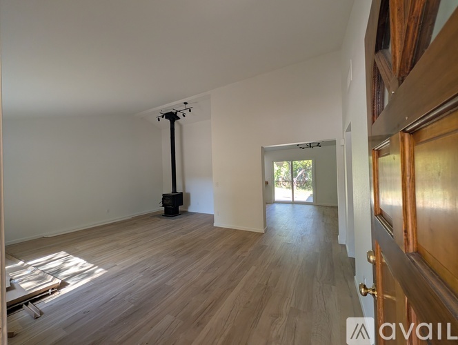 A room with wooden flooring and a white ceiling with a black pipe running up it.