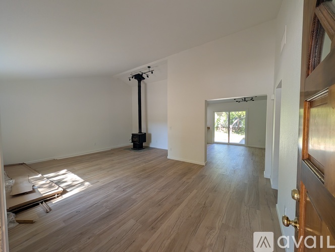 A room with wooden flooring and a white wall with a door on the right side.