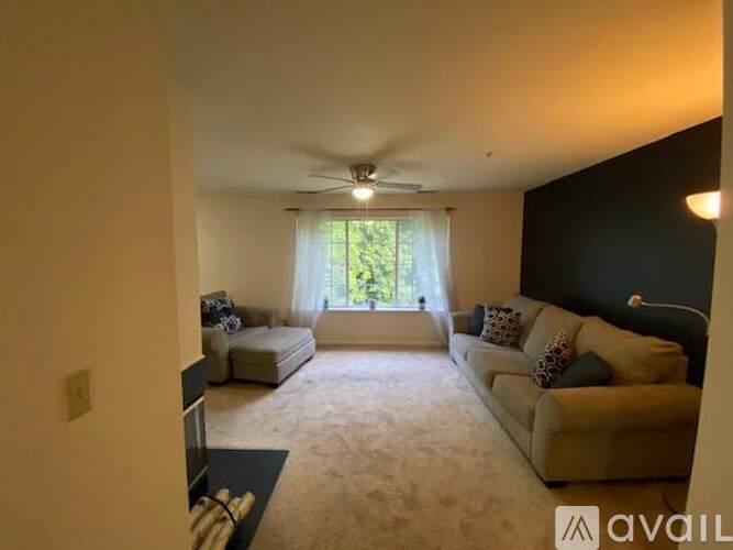 A living room with a beige sofa and a ceiling fan.