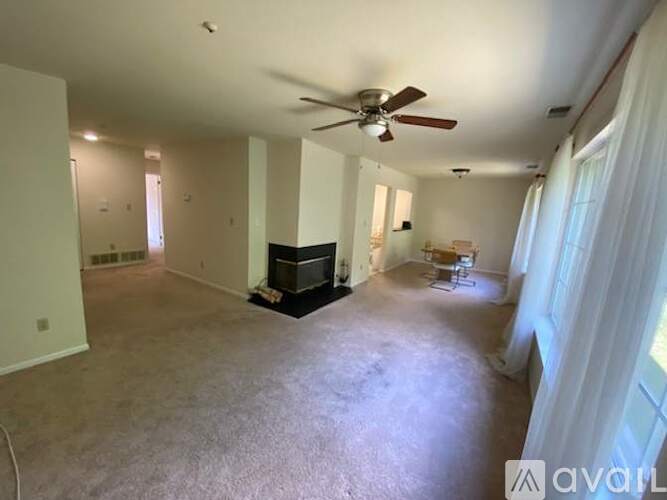 A living room with a fireplace and a ceiling fan.