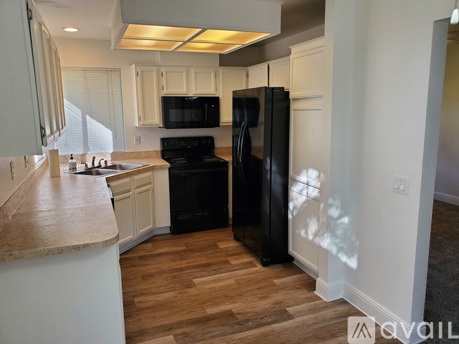 A kitchen with black appliances and wooden floors.