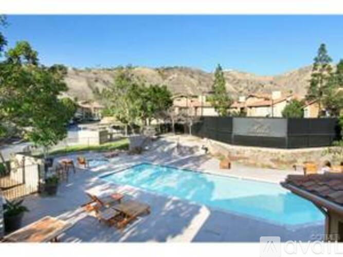 A large outdoor swimming pool surrounded by a wooden deck and a mountainous landscape.