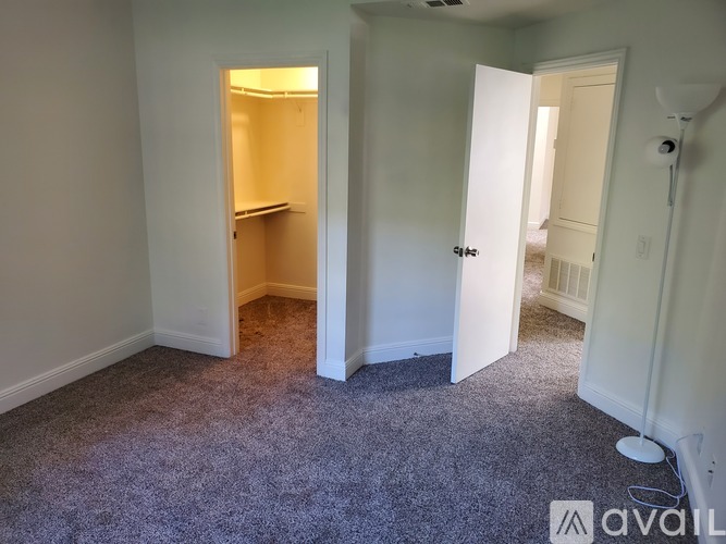 A room with carpeted floor and two open doors.