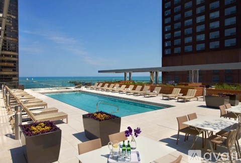 A pool area with chairs and a table with flowers on it.