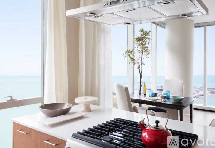A modern kitchen with a red kettle on the stove.