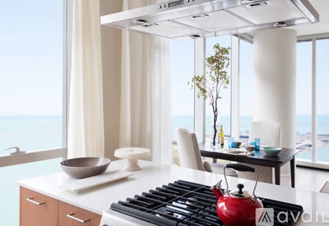 A modern kitchen with a red kettle on the stove.