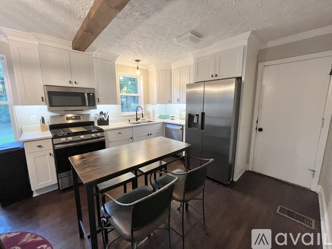 A kitchen with a table and chairs in front of a refrigerator.