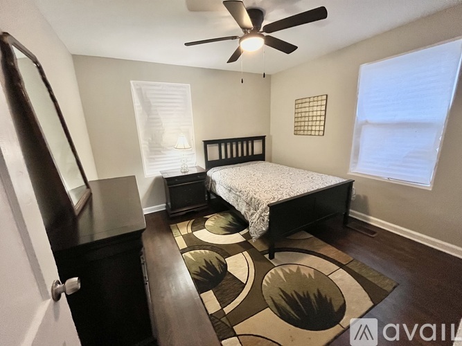 A bedroom with a bed, dresser, and a rug with circular designs.