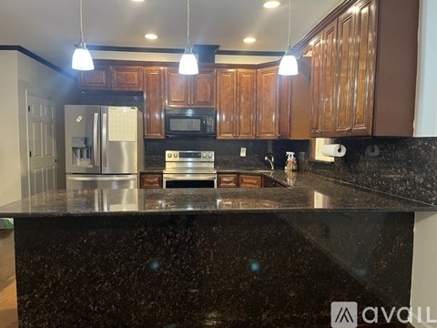 A kitchen with brown cabinets and a black granite countertop.