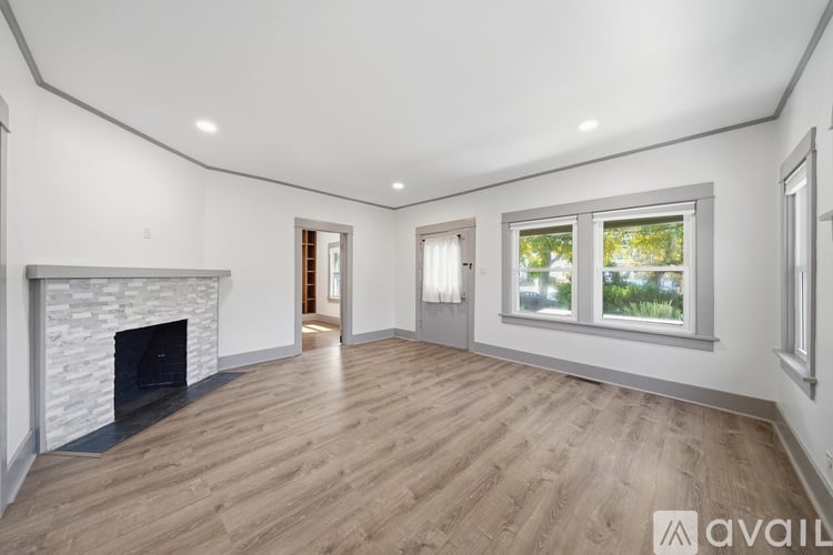 A spacious room with a fireplace and wooden flooring.