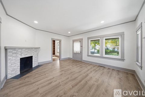 A spacious room with a fireplace and wooden flooring.