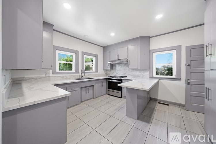 A modern kitchen with a large island and a view of the outdoors through the windows.