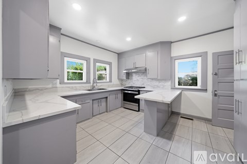 A modern kitchen with a large island and a view of the outdoors through the windows.