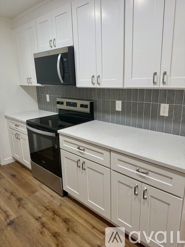 A kitchen with white cabinets and a black microwave.