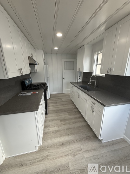 A kitchen with white cabinets and black countertops.