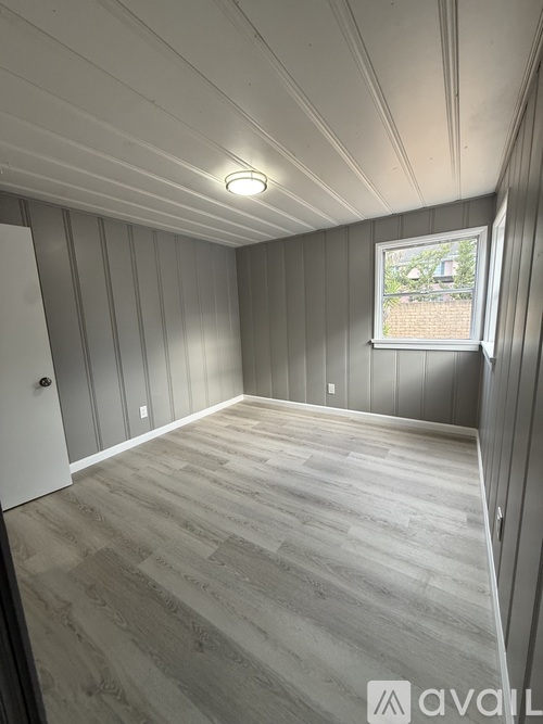 A room with wooden flooring and a window showing a building outside.
