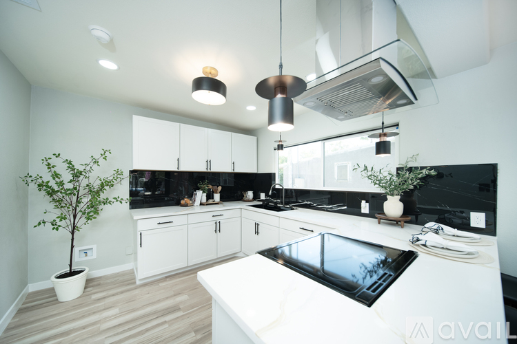 A modern kitchen with black countertops and white cabinets.