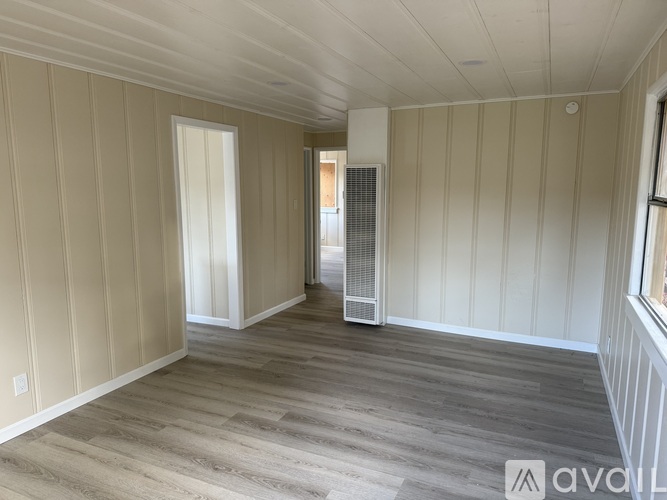 A room with wooden flooring and white walls.