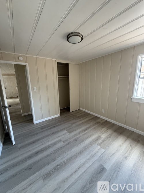 A room with wooden flooring and a window on the right side.