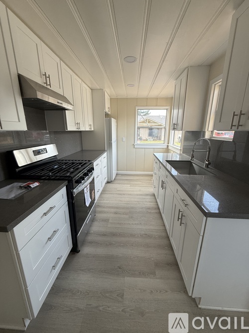 A kitchen with white cabinets and black countertops.