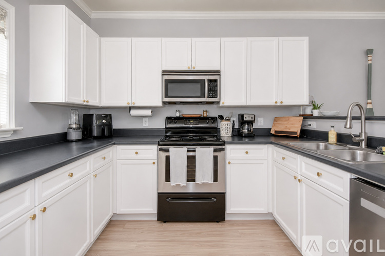 A kitchen with white cabinets and black countertops.