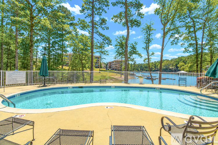 A pool surrounded by trees and chairs.