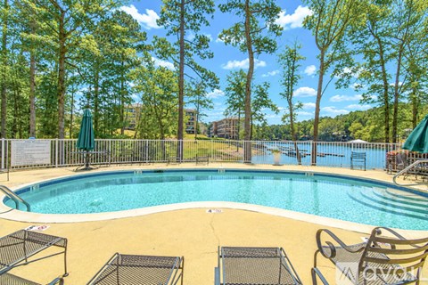 A pool surrounded by trees and chairs.