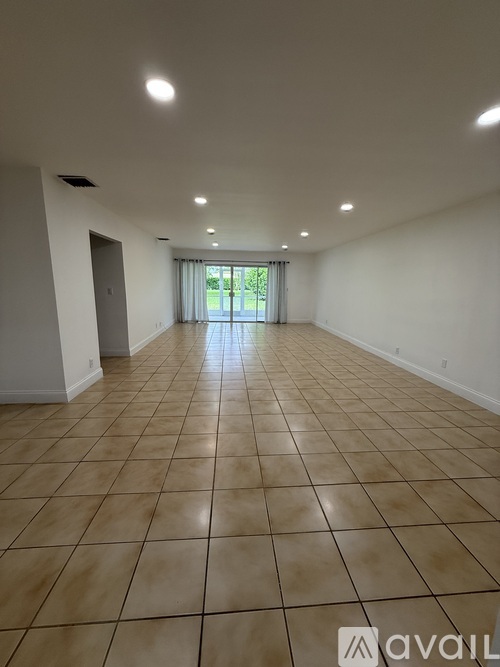 A spacious room with tiled flooring and a view of greenery outside the window.