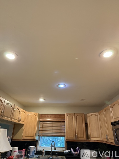 A kitchen with wooden cabinets and a sink under a counter.