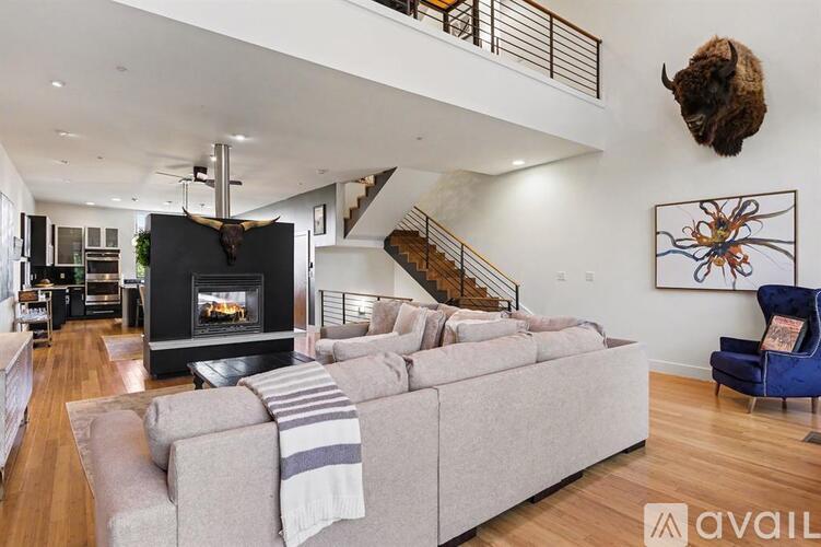 A living room with a grey couch and a fireplace.