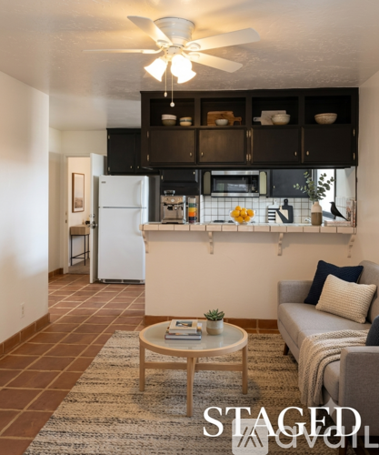 A living room with a couch, a coffee table, and a kitchen area in the background.