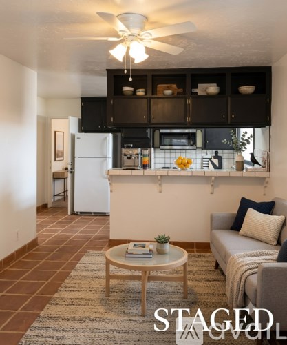 A living room with a couch, a coffee table, and a kitchen area in the background.