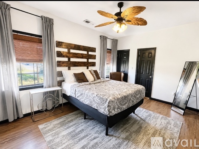 A bedroom with a bed, a ceiling fan, and a window with curtains.