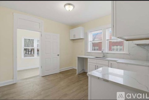 A kitchen with a white countertop and wooden flooring.