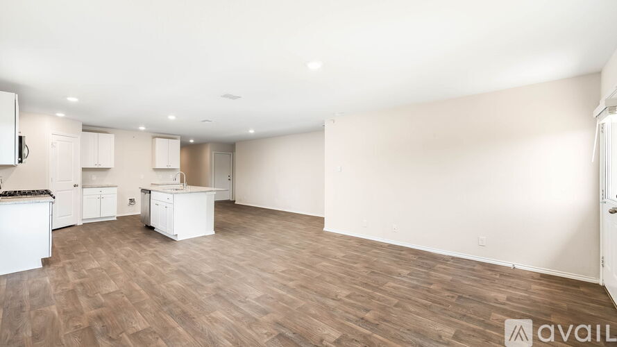 A spacious kitchen with white cabinets and a wooden floor.