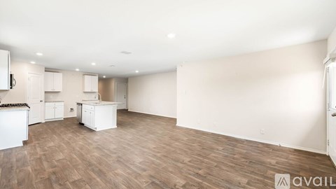 A spacious kitchen with white cabinets and a wooden floor.