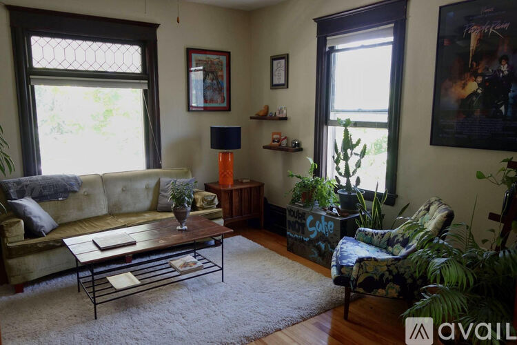 A living room with a couch, chair, and potted plants.