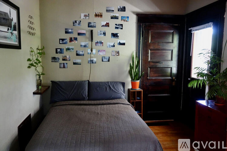 A bedroom with a bed, a wall with pictures, and a door.