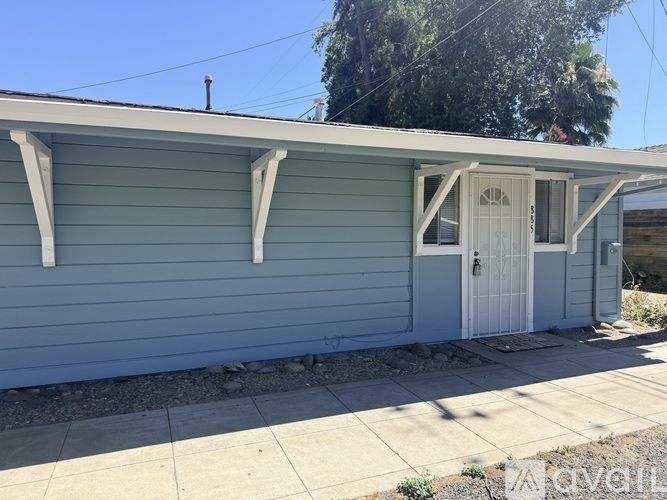 A small blue house with a white door and window.