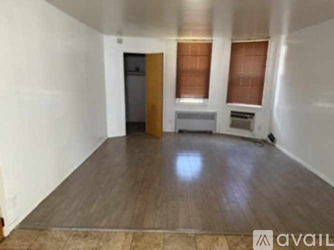 A room with a wooden floor and a white wall with a door and a window.