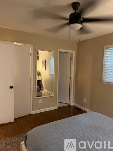 A bedroom with a bed, a ceiling fan, and a mirrored door.